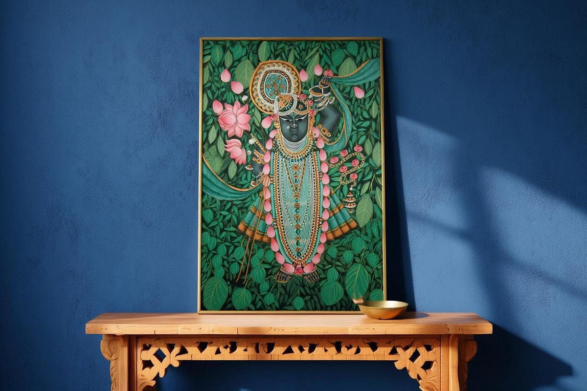 a framed painting of a Hindu deity, likely a representation of the Hindu deity Krishna, displayed on a wooden table against a blue wall.