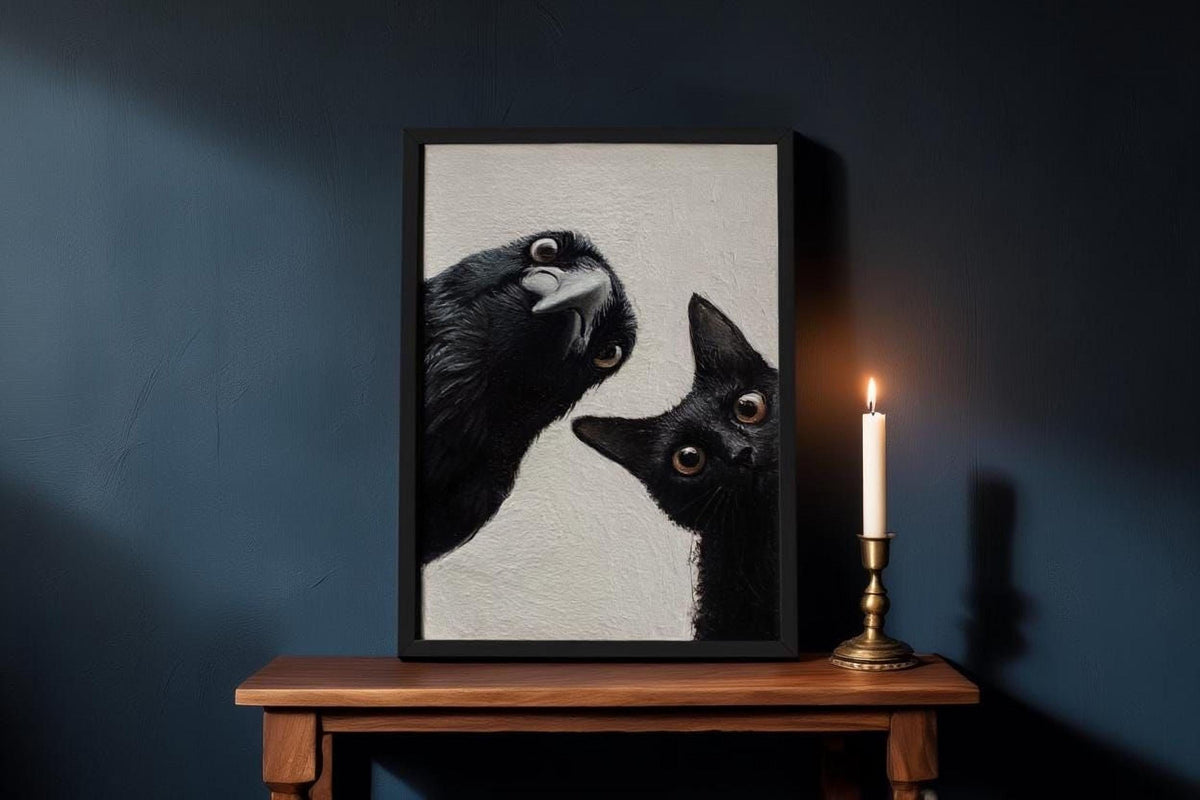 a framed painting of two black cats with wide-open eyes, one looking up and the other looking down, placed on a wooden table next to a lit candle.