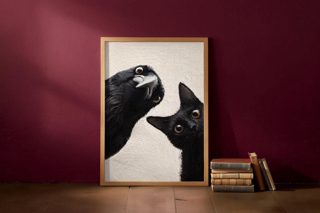 A framed photograph of two black cats peeking out from behind a white background, with a stack of books and a red wall in the background.