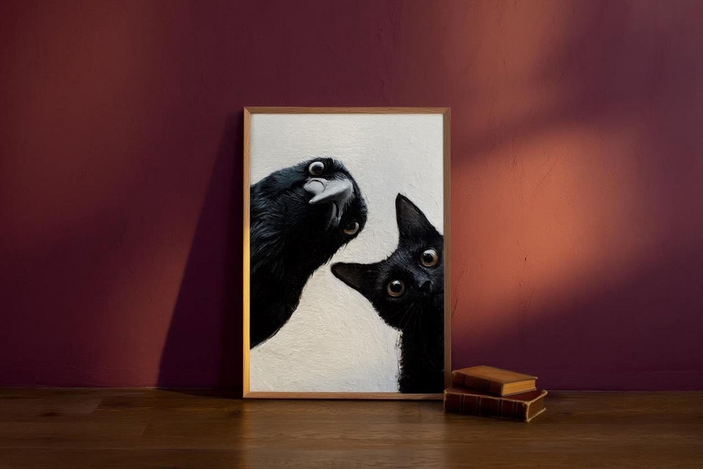 A framed photograph of a black cat and a black bird is displayed on a wooden floor against a red wall, with a stack of books and a shadow cast on the wall behind the frame.