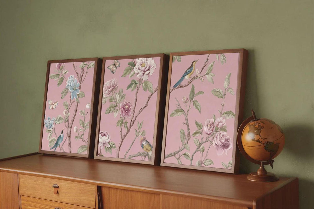 A wooden dresser with three framed floral paintings on it, each depicting a different type of flower and bird. A globe is also present on the dresser.