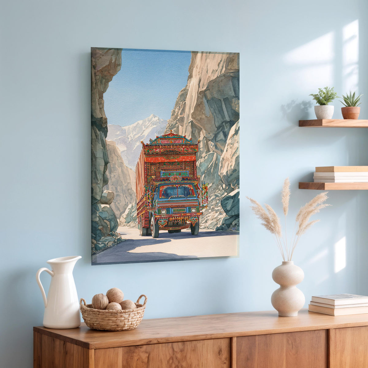 a colorful truck driving through a mountainous landscape, with a wooden shelf displaying decorative items and a basket of nuts on a table below.