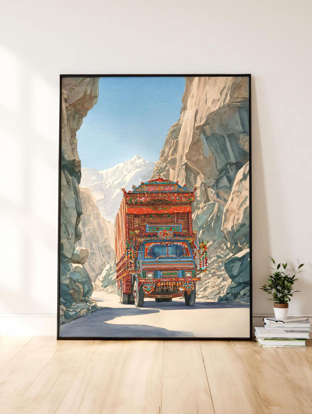 A large framed painting depicting a colorful truck driving through a mountainous landscape with a clear blue sky.