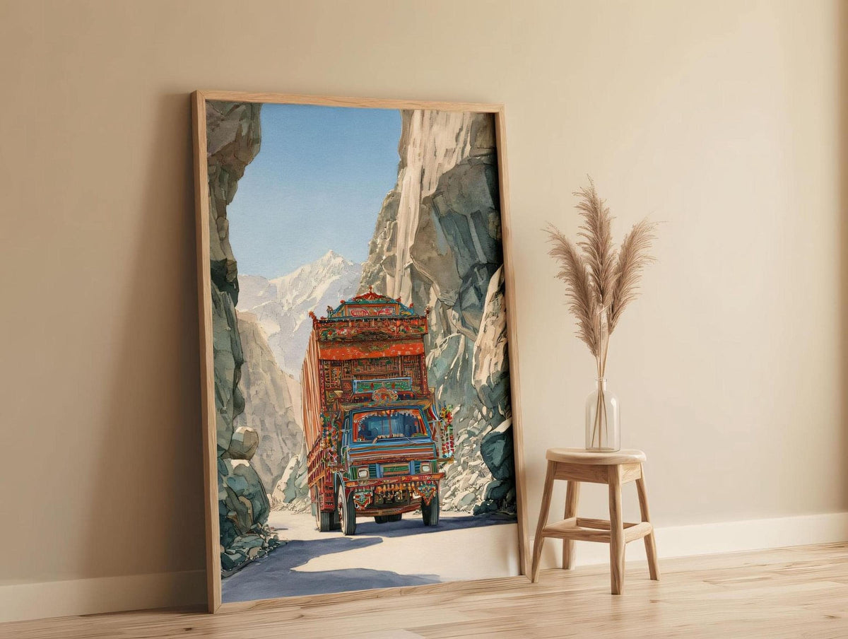 a large, colorful painting of a truck driving through a mountainous landscape, with a wooden stool and a potted plant in the foreground.