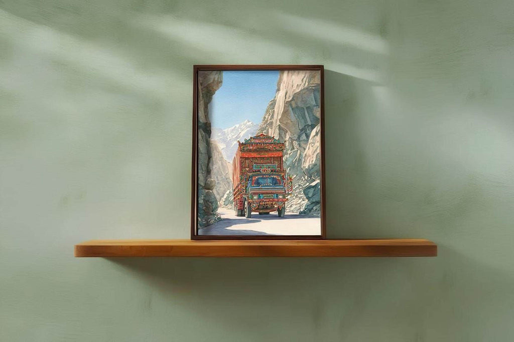 A framed photograph of a colorful truck driving through a mountainous landscape is displayed on a wooden shelf against a green wall.