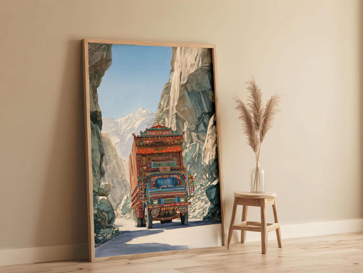 a large, colorful painting of a truck driving through a mountainous landscape, with a wooden stool and a potted plant in the foreground.