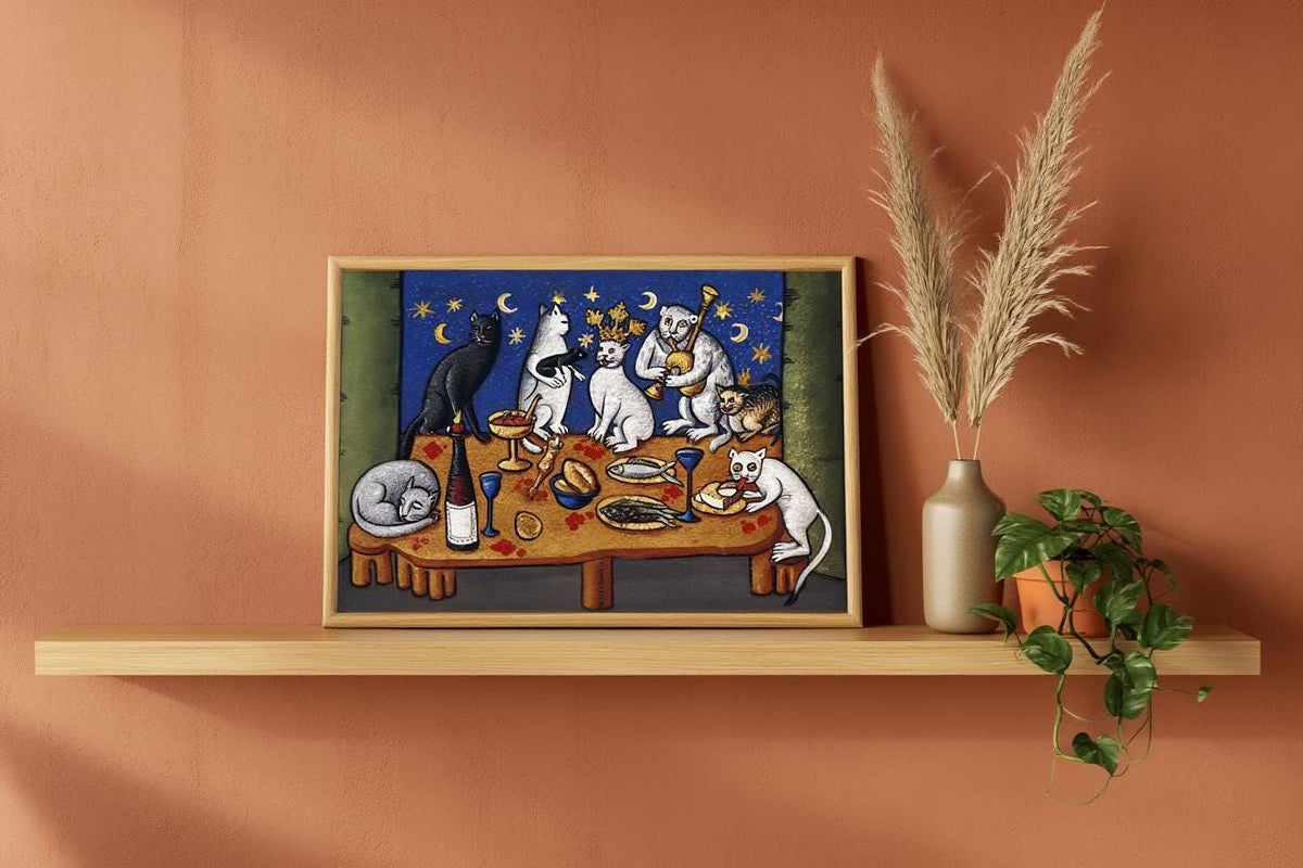 a framed painting of cats sitting around a table with food, including a wine glass, a bowl, and a vase. The painting is displayed on a wooden shelf, and there is a potted plant and a vase with a plant on the shelf as well.