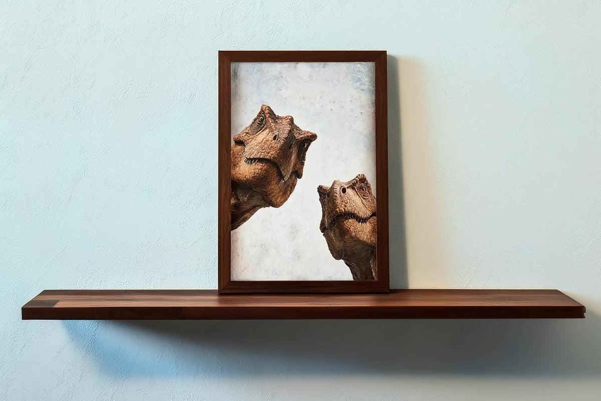 two dinosaur heads, possibly T-Rex, displayed in a wooden frame on a shelf against a light blue wall.