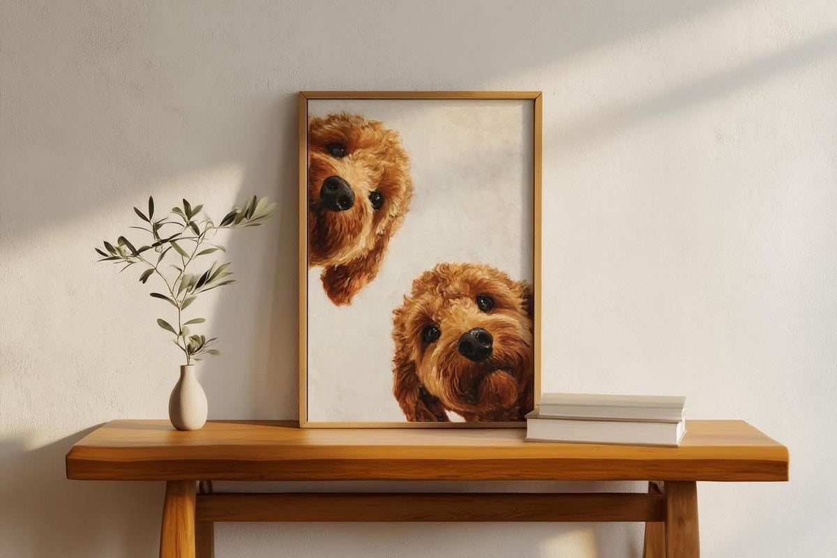 two brown dogs peeking out from behind a framed picture on a wooden table.