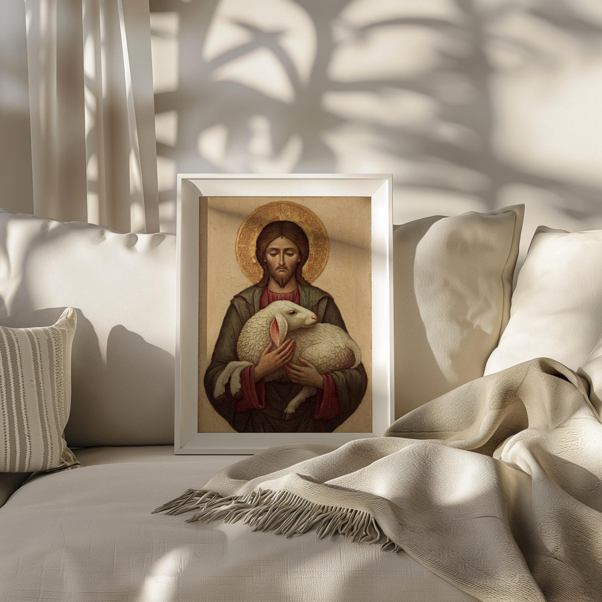 A framed painting of Jesus Christ holding a lamb is displayed on a white couch, with a striped pillow to the left and a beige blanket to the right.