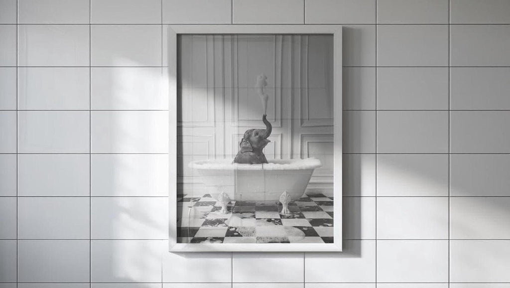 A framed black and white photograph of an elephant sitting in a bathtub, with its trunk raised in the air.