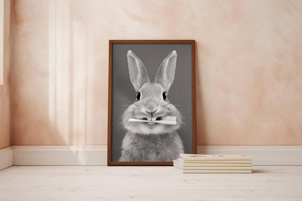 A framed black and white photograph of a rabbit holding a toothbrush in its mouth, placed on a wooden floor next to a stack of books.