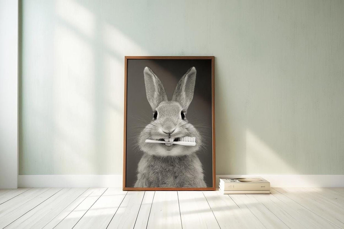 A framed black and white photograph of a rabbit holding a toothbrush in its mouth, standing on a wooden floor against a light green wall.