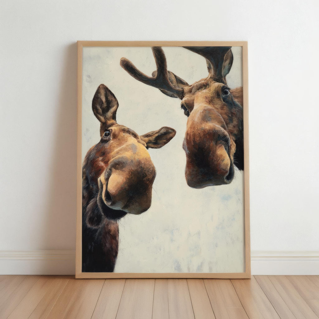 Framed moose print leaning on wood floor, close-up playful face, warm browns, funny moose wall art printable