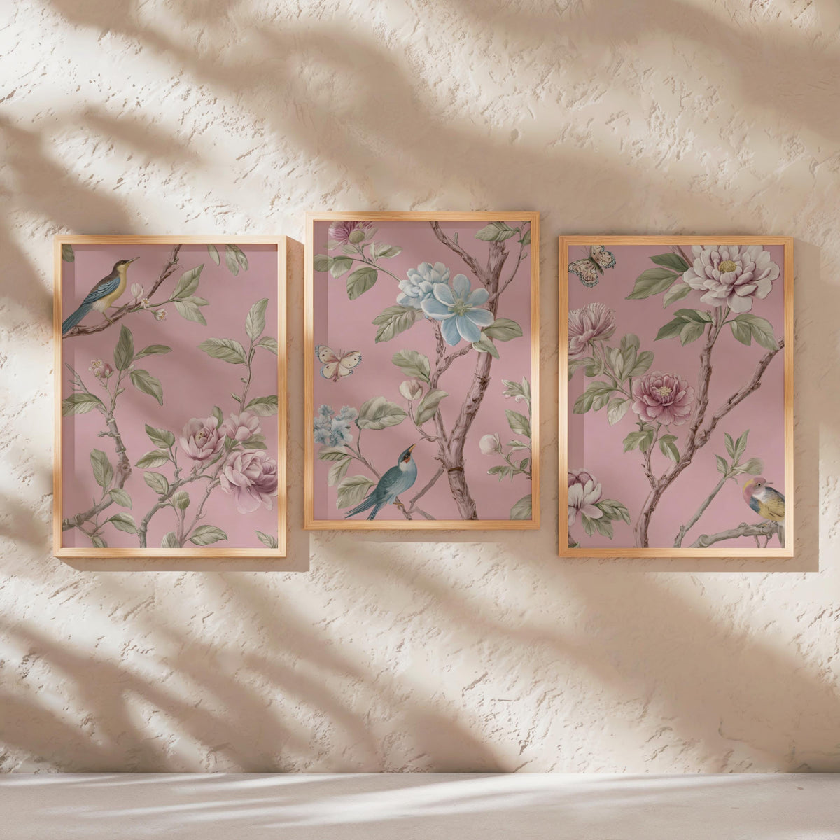 three framed pictures of birds perched on branches with flowers, displayed on a wall.