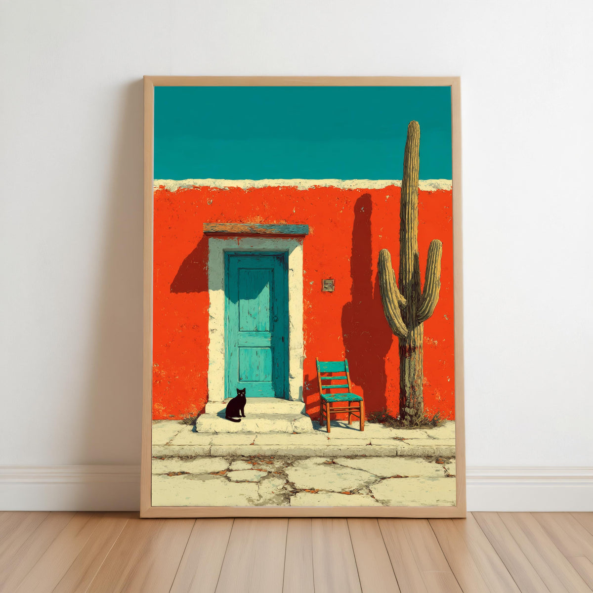 Framed southwestern desert wall art leaning on wood floor, red-orange stucco, turquoise door, saguaro, black cat on blue chair