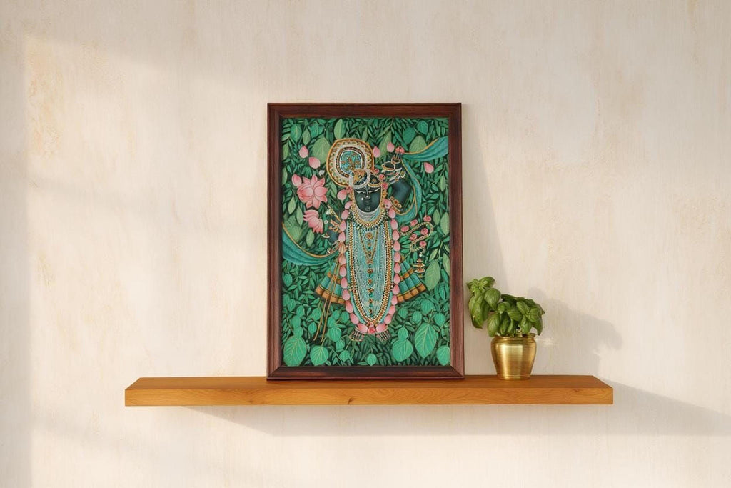 a framed painting of a Hindu deity, surrounded by a lush green background with flowers, placed on a wooden shelf next to a potted plant.