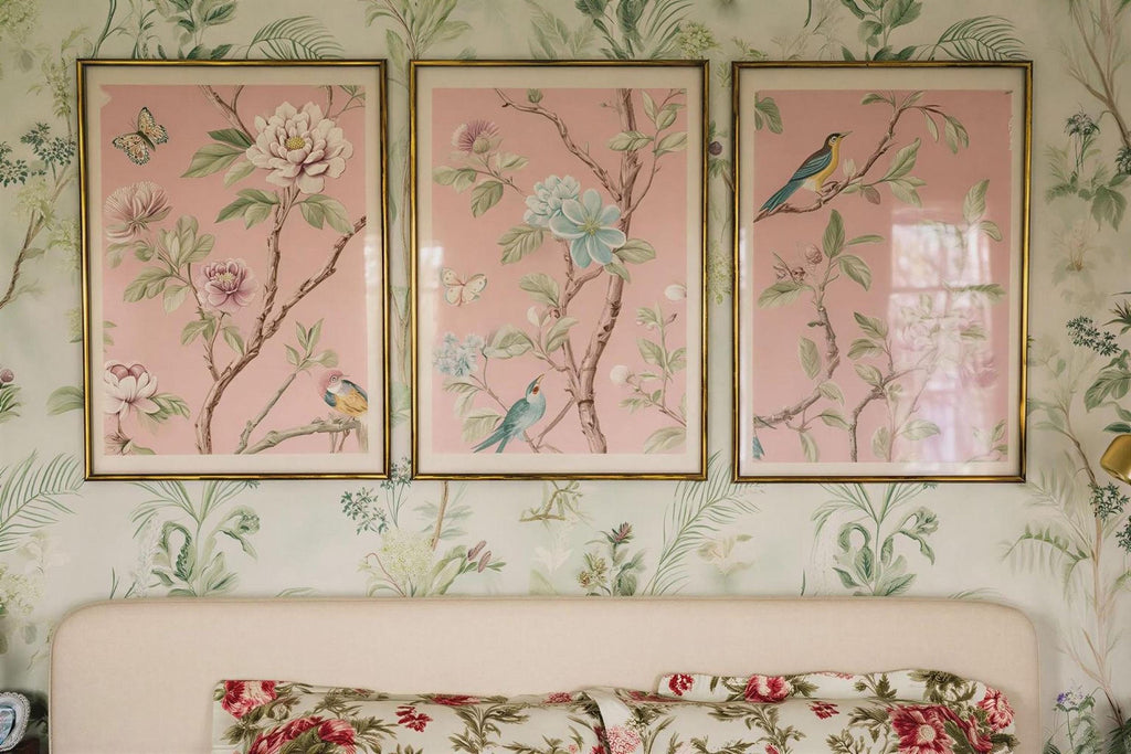 a bedroom with a white headboard and a floral bedspread. Above the bed, there are three framed pictures of flowers hanging on the wall.
