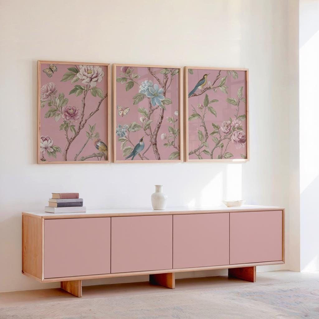a pink cabinet with three framed floral wall art pieces above it, creating a cohesive and visually appealing design.