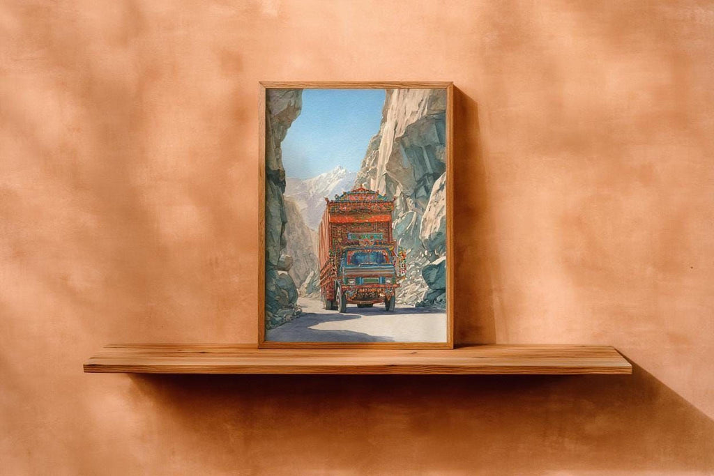 a wooden shelf displaying a framed painting of a colorful truck driving through a mountainous landscape.