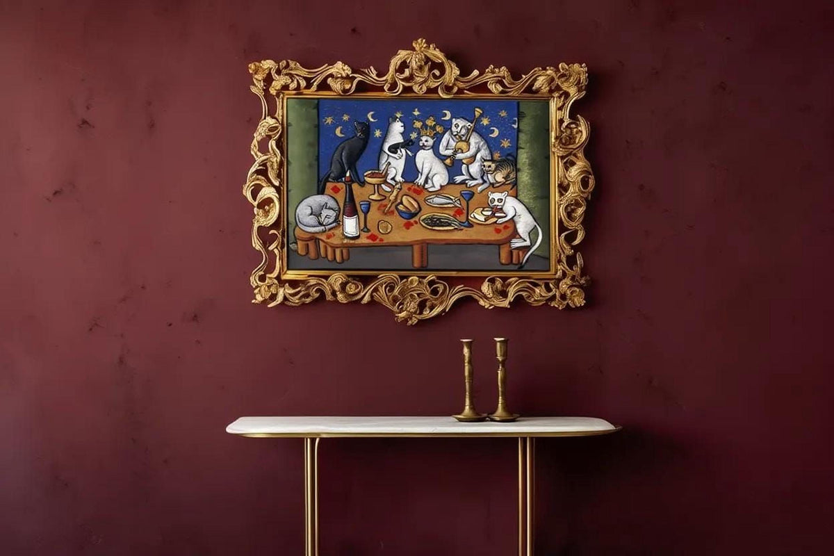 a painting of cats sitting around a table with food, displayed on a wall above a white table with two candlesticks.