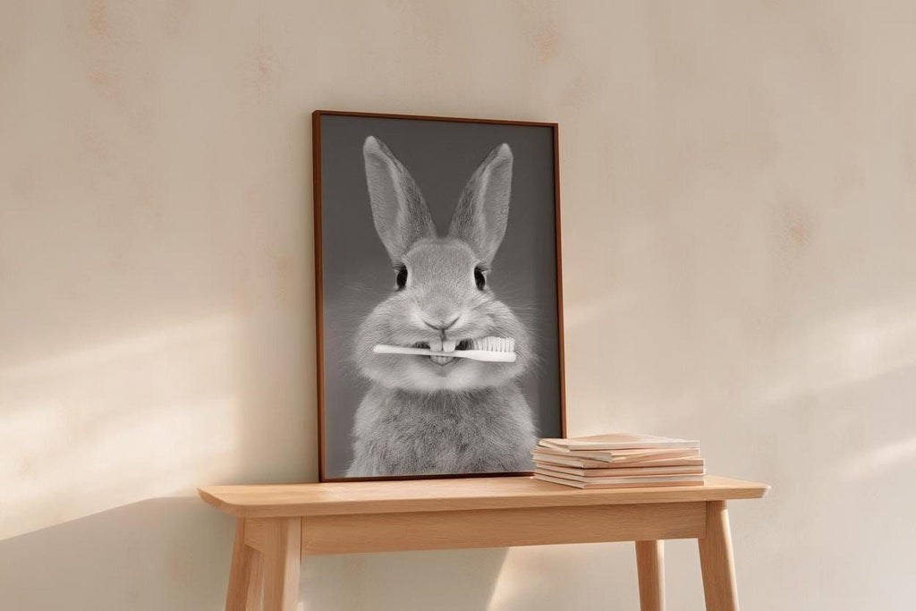 A framed black and white photograph of a rabbit holding a toothbrush in its mouth is displayed on a wooden table.