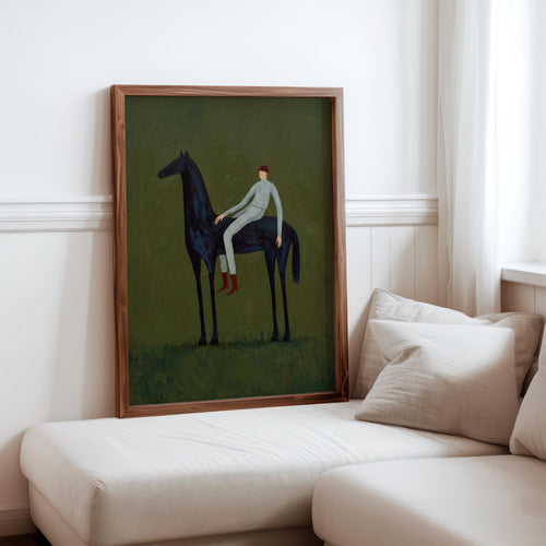 Framed vintage equestrian wall art displayed on living room sofa, slim wood frame, olive green tones.