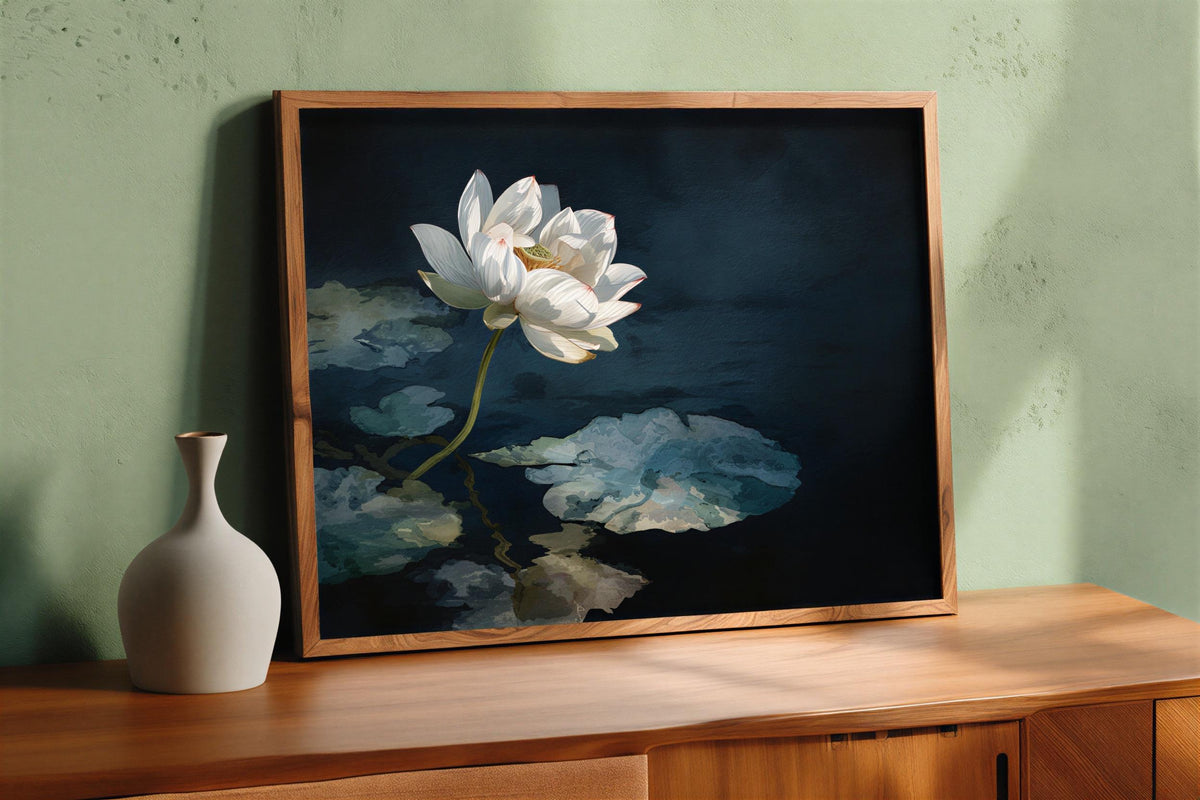 Framed white lotus wall art atop a wooden dresser against soft green paint, moody lotus print, Asian botanical wall decor vignette