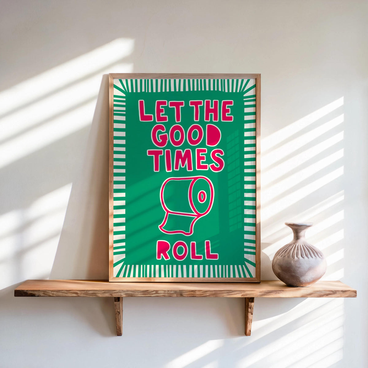 Teal background poster with pink lettering leaning on shelf, colorful bathroom print and toilet paper bathroom decor