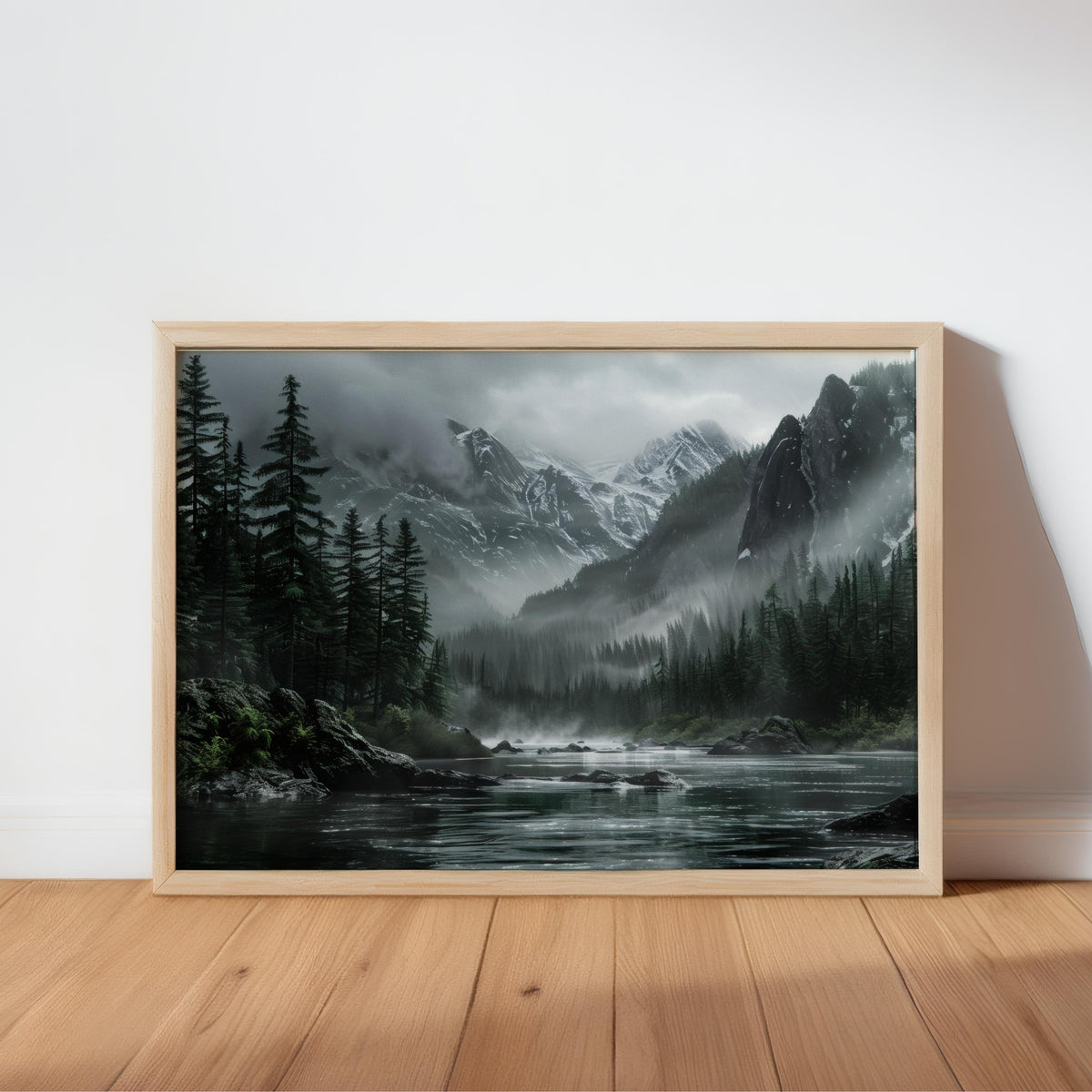 Oak-framed moody mountain landscape wall art leaning on wood floor, misty forest river foreground