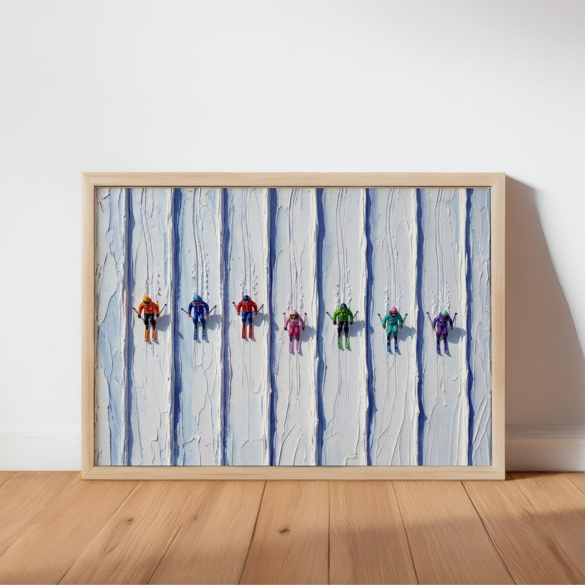 Framed vintage ski art print leaning on warm wood floor, tiny retro skiers on impasto snow