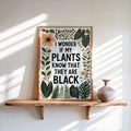 Framed poster on a sunlit wooden shelf, terracotta vase, bold botanicals, black plant lover wall art
