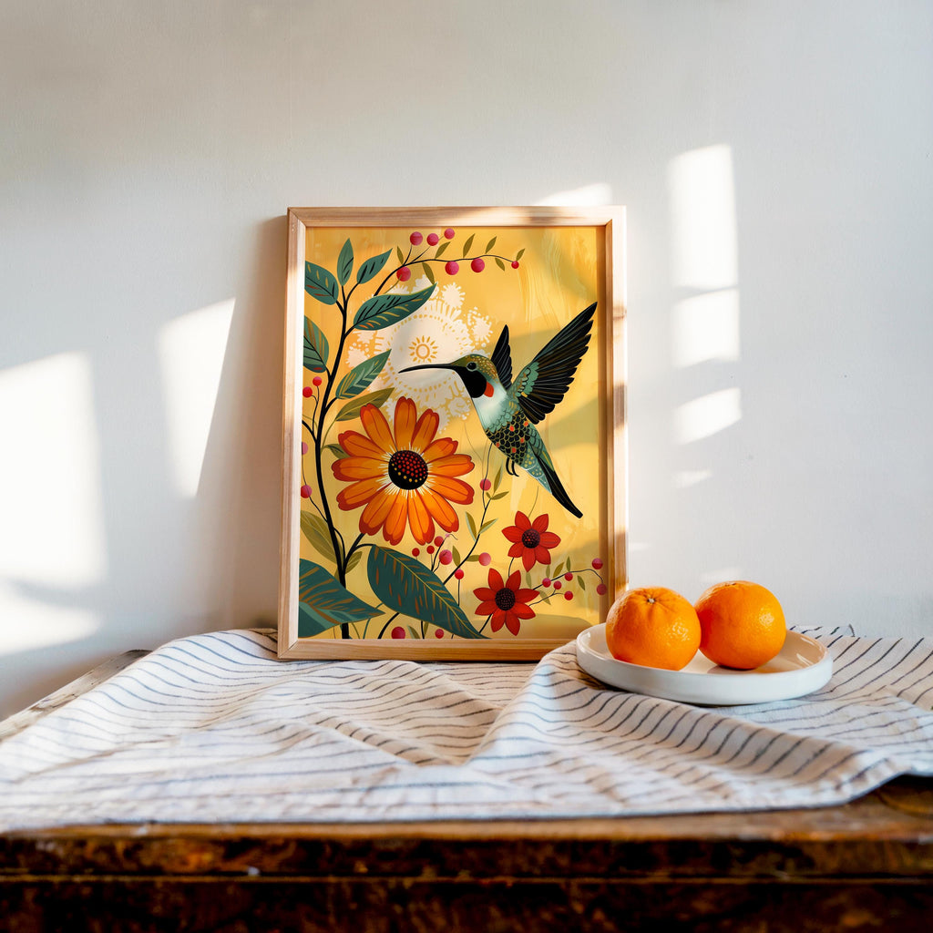 Print on wooden table by sunlit window, orange hummingbird art with marigold flowers, bright cozy styling.