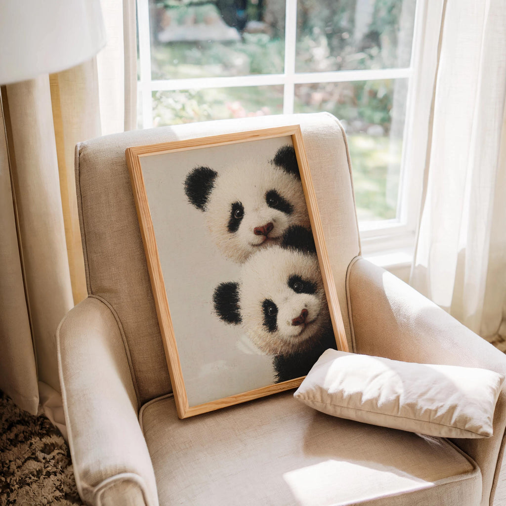 Baby pandas wall art: two giant panda cubs peeking from the edge in a light-wood framed print for baby panda nursery decor.