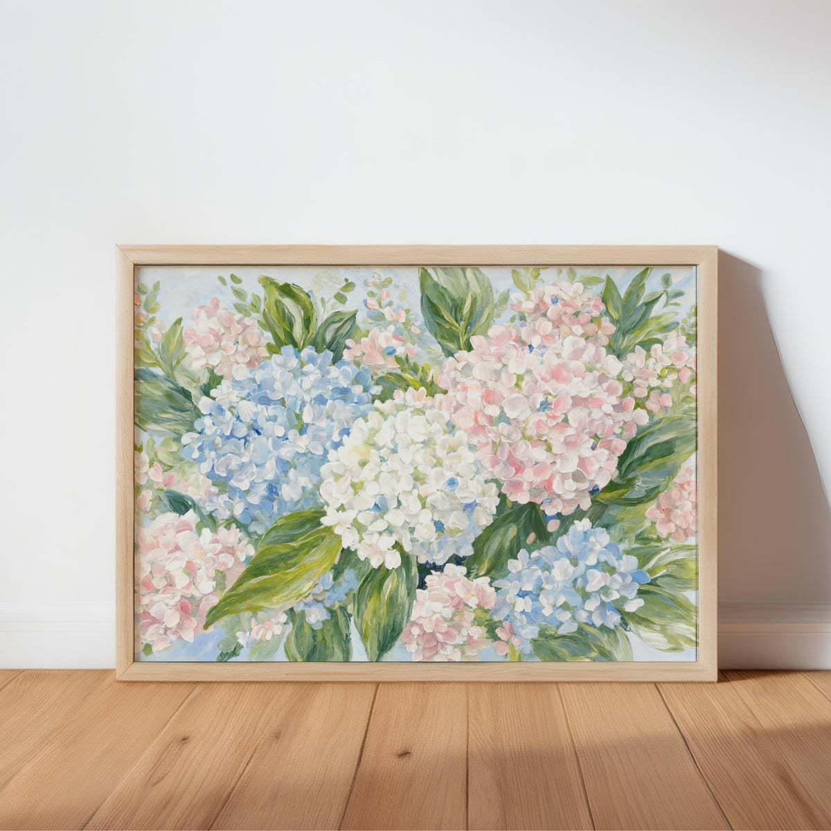 Pastel hydrangea wall art, framed and leaning on hardwood, soft blue and blush pink blossoms