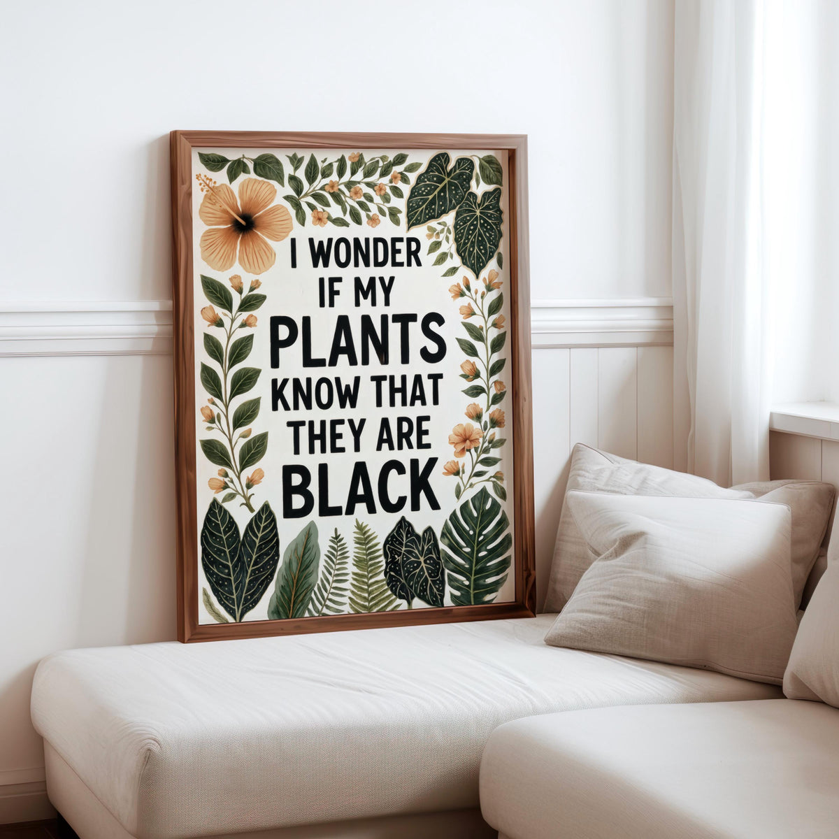 Low sofa corner with cushions, framed botanical typography resting beside seat, black plant lover wall art