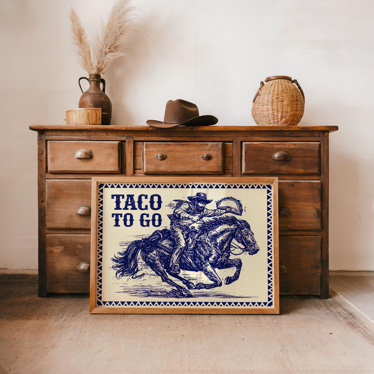 Blue ink framed print displayed leaning by rustic sideboard, southwestern kitchen wall decor vibe, cowboy taco poster