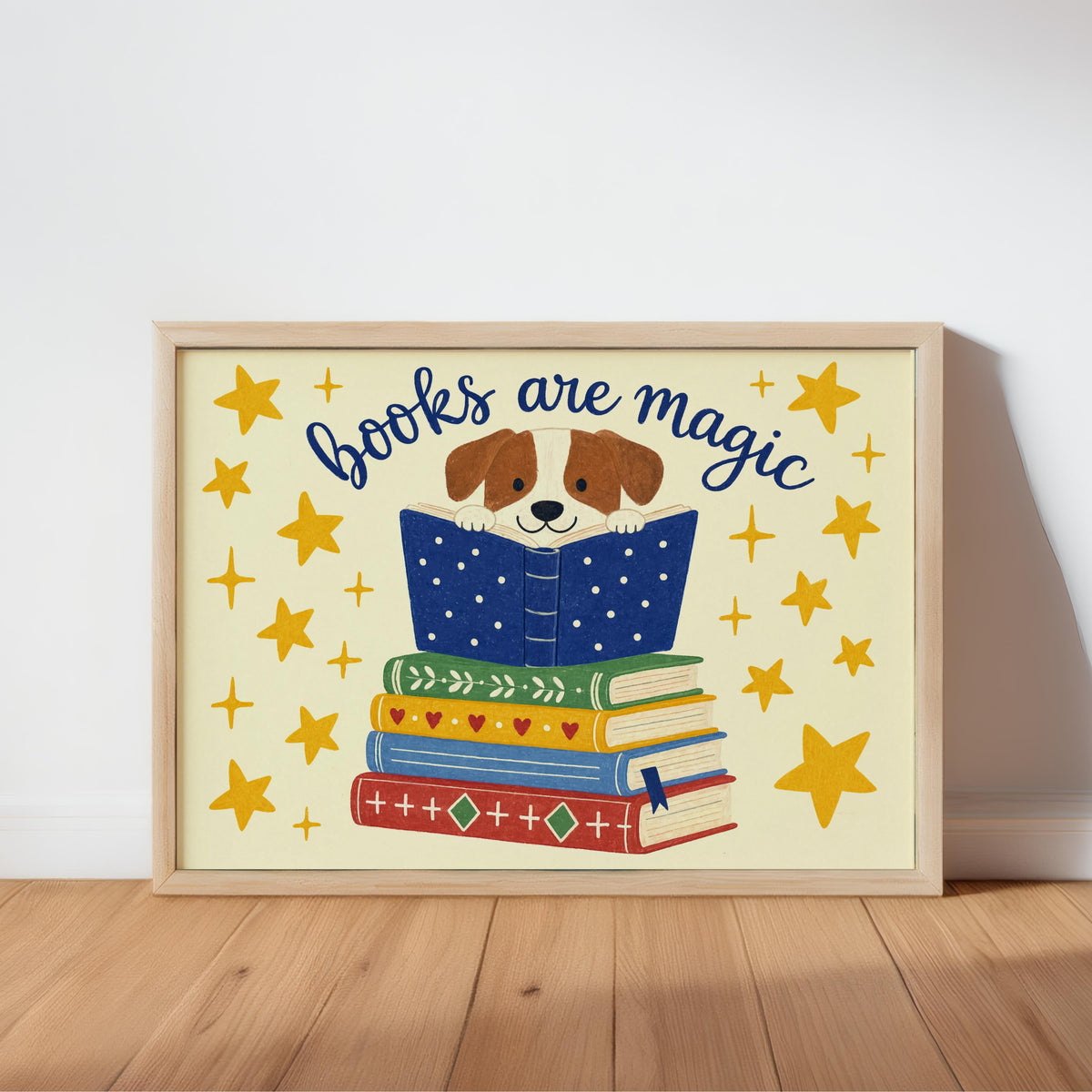 Framed dog reading wall art leaning on warm wood floor, cream background, blue book stack, yellow stars