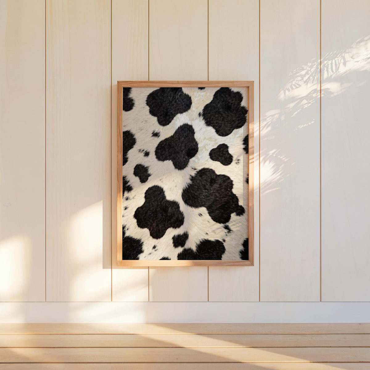 Cow print wall art centered on white shiplap, natural light and minimalist farmhouse styling