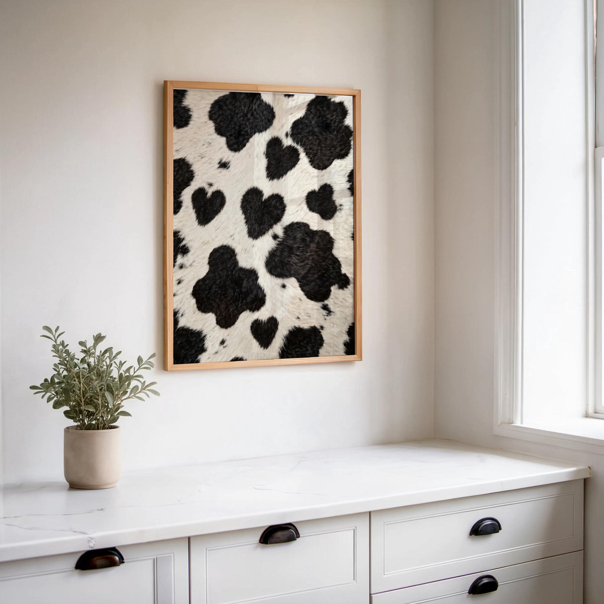 Heart cow print wall art hung above a white console, small potted plant, clean rustic farmhouse styling
