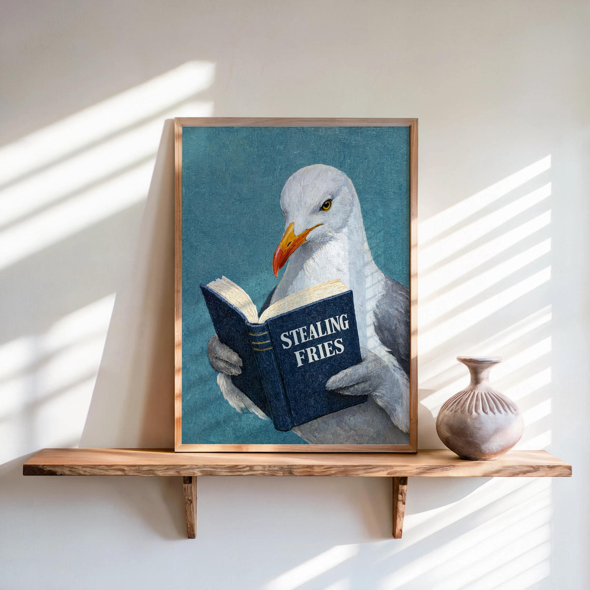 Teal background framed on shelf, navy book titled Stealing Fries, whimsical, funny seagull reading art print