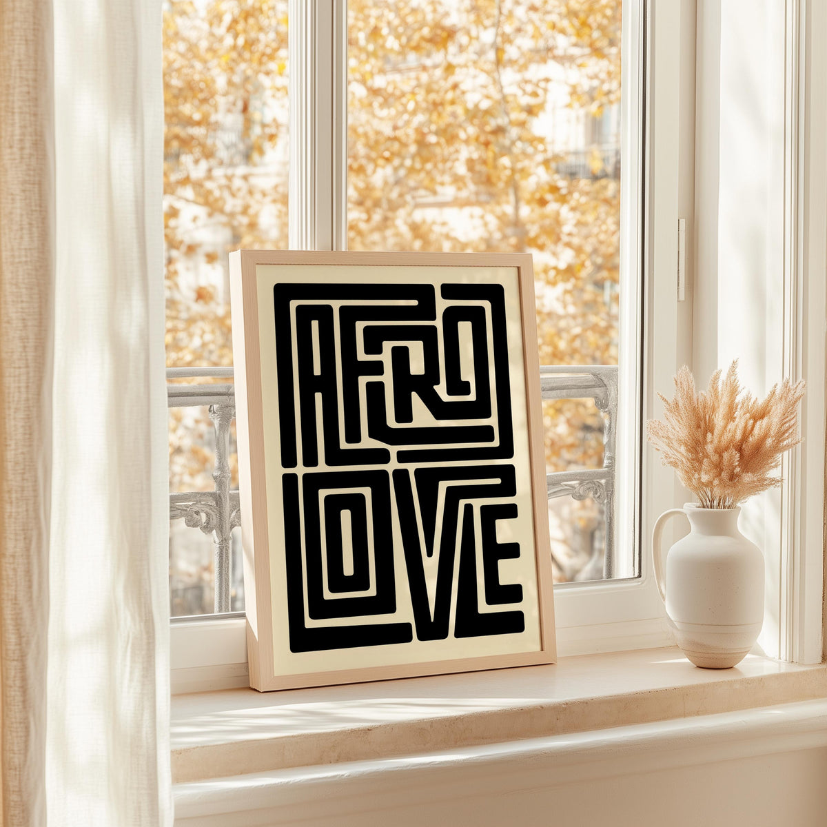 Afro Love wall art framed on bright windowsill, autumn light and a vase, minimalist Black and white typography art