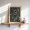 Afro Love wall art framed print on floating wood shelf, sunlit wall, small ceramic vase nearby