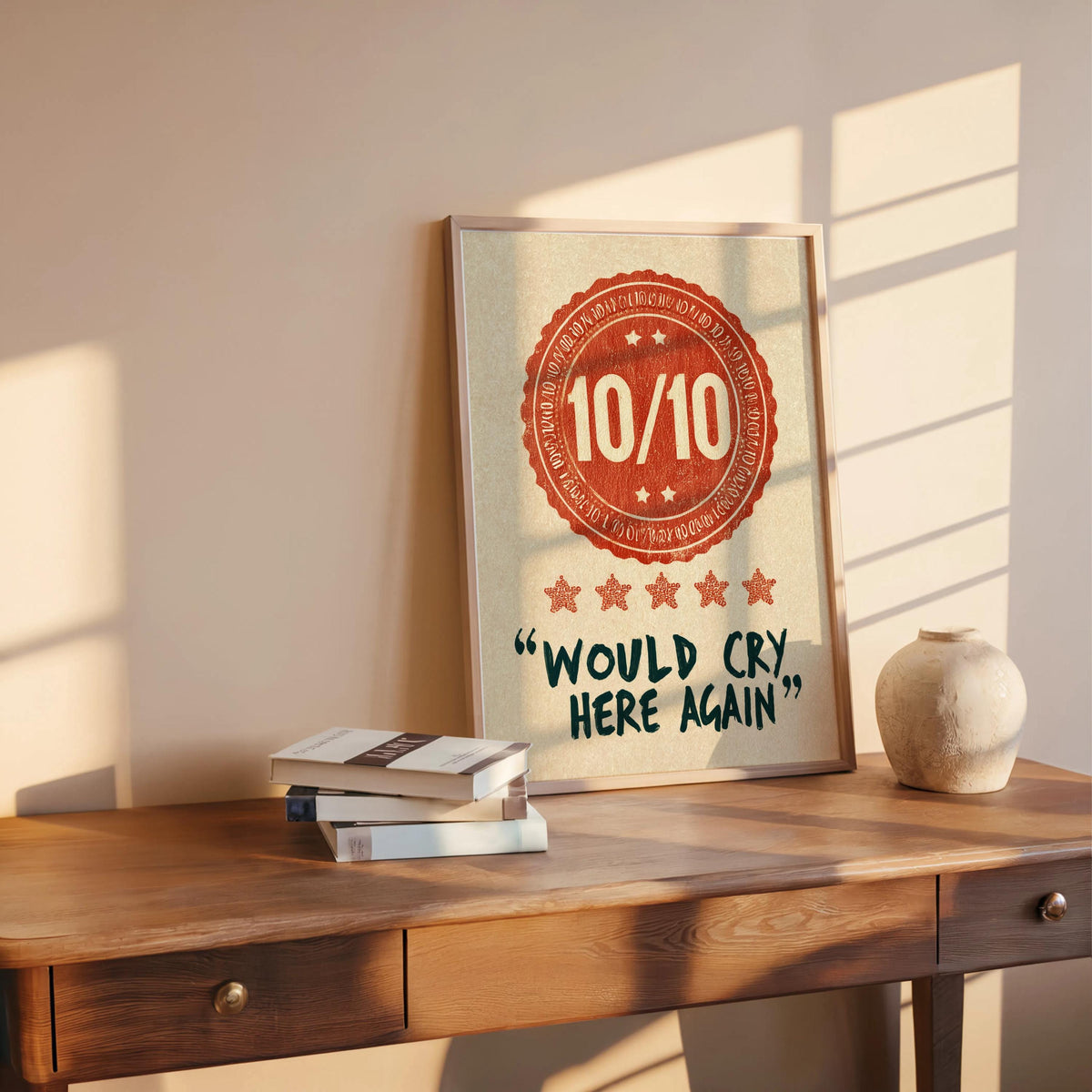Orange would cry here again print on a mid-century desk, sunlight, stacked books, playful dark humor wall art