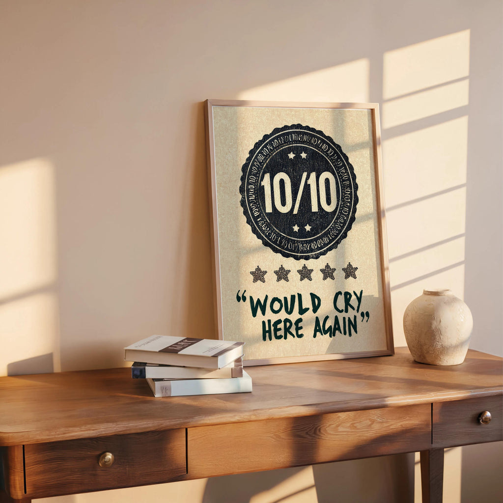 Navy would cry here again print propped on a wooden desk, books and stone vase, warm evening light