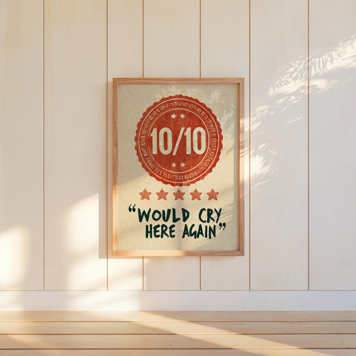Centered would cry here again print in orange, framed against white paneled wall, clean minimalist styling