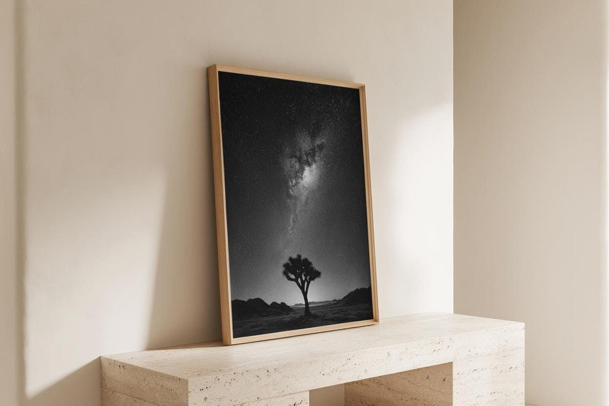 Corner display with framed poster leaning on a stone shelf, desert night sky wall art bathed in daylight