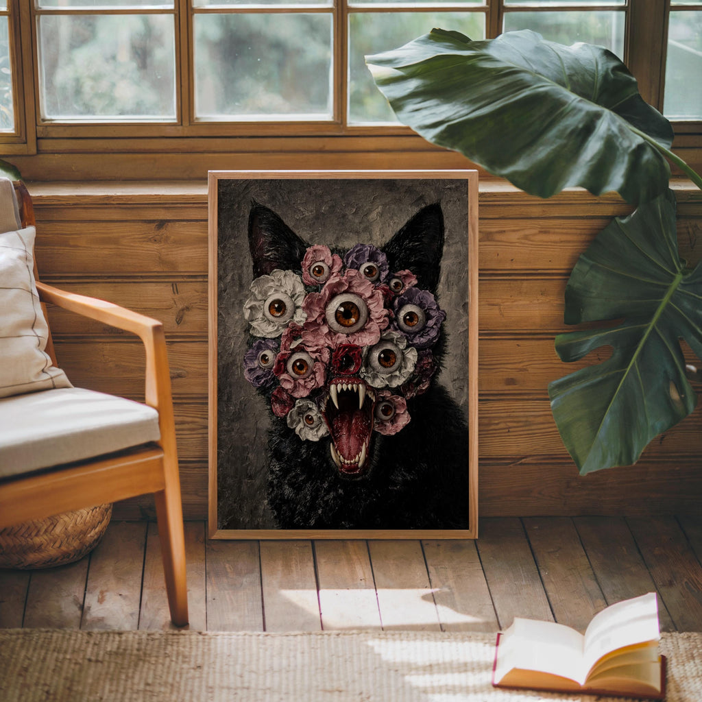 Gothic cat wall art in a wooden frame beside a rattan chair and large leaf, a black cat floral wall art print