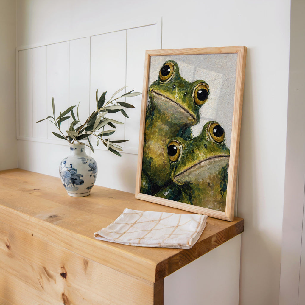 Frog art print leaning on a wooden console, potted plant nearby, warm morning light, rustic feel.