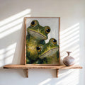 Framed funny frog wall art leaning on a sunlit wooden shelf, impasto texture, earthy green frogs.